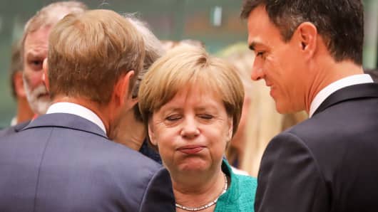 Germany's Chancellor Angela Merkel reacts as she speaks with European Council President Donald Tusk (L) and Spain's Prime Minister Pedro Sanchez (R).