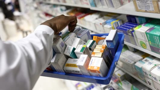 A pharmacist collects medications for prescriptions at a pharmacy.