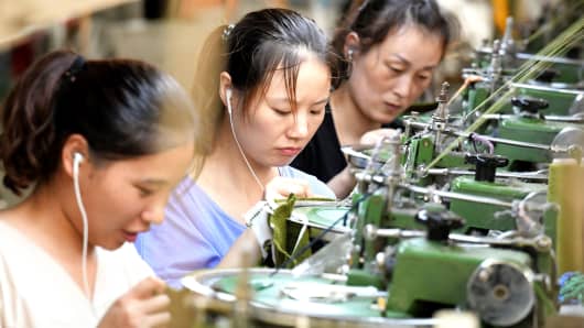 Employees working on a production line of clothes for export at a factory in Xiayi county, in Shangqiu in China's central Henan province.