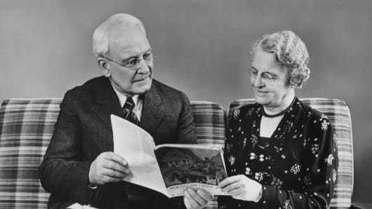 Senior couple reading travel book at home
