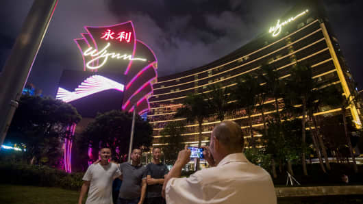 People pose for photographs in front of the Wynn Macau casino resort in Macau, China, on Tuesday, July 24, 2018.