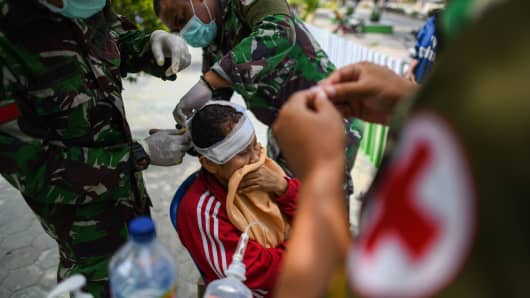 Indonesian Army medics treat an injured woman at a makeshift camp in Palu in Central Sulawesi on October 4, 2018, after an earthquake and tsunami hit the area on September 28.