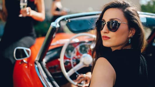 Young fashionable girl driving an oldtimer convertible sportscar