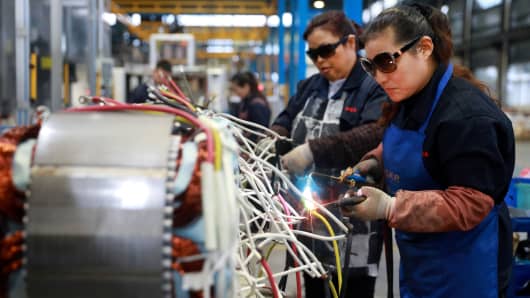 Women wearing sunglasses work at a production line manufacturing electric machine parts at a factory in Luan, China November 17, 2018.