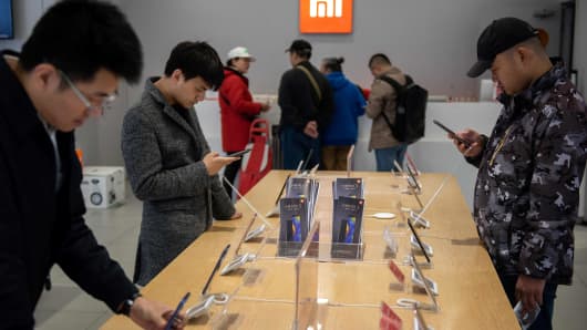 Customers look at mobile phones in a Xiaomi shop in Beijing on November 7, 2018. (Photo by Nicolas ASFOURI / AFP)        (Photo credit should read NICOLAS ASFOURI/AFP/Getty Images)