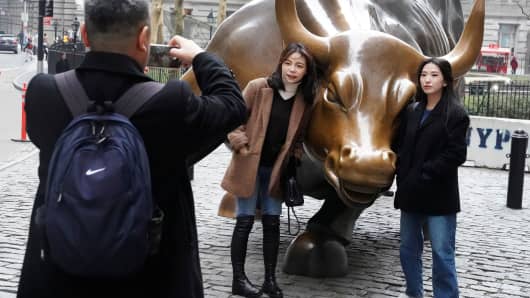 People pose for photos with the Charging Bull near Wall Street in New York City, January 16, 2019.
