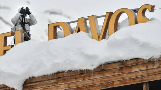 A policeman wearing camouflage clothing stands on the rooftop of a hotel, next to letters covered in snow reading "Davos," near the Congress Centre ahead of the World Economic Forum (WEF) annual meeting on January 21, 2019 in Davos, Switzerland.