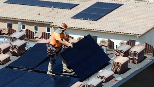 Workers install solar panels on the roofs of homes under construction south of Corona, California. The California Energy Commission in May 2018 adopted new energy building standards requiring solar panels for virtually all new homes built in the state starting in 2020.