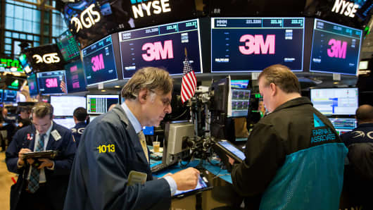 Merchants work under screens displaying 3M Co.'s signage on the floor of the New York Stock Exchange (NYSE) in New York.
