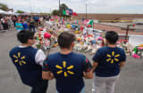 Walmart employees pay their respects at a makeshift memorial for the shooting victims, at the Cielo Vista Mall Walmart in El Paso, Texas, on August 6, 2019. - The August 3 shooting left 22 people dead. US President Donald Trump will visit the Texan border city August 7, and will also travel to Dayton, Ohio where a second mass shooting early August 4 left another nine dead
